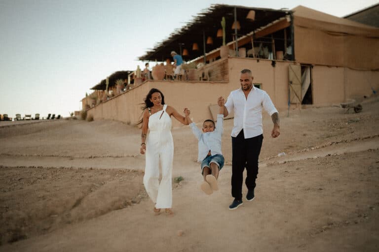 Vanessa and Soufian lift their child by the hands during their family photo session in Agafay