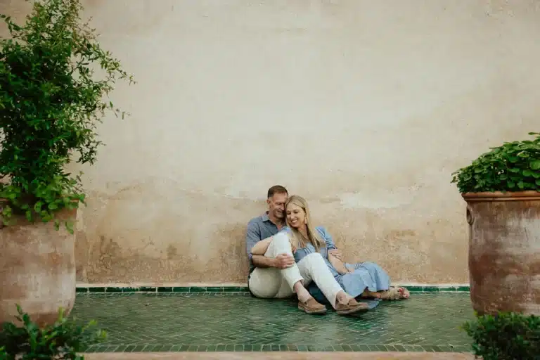 Two adults seated together against an ochre wall in Marrakech
