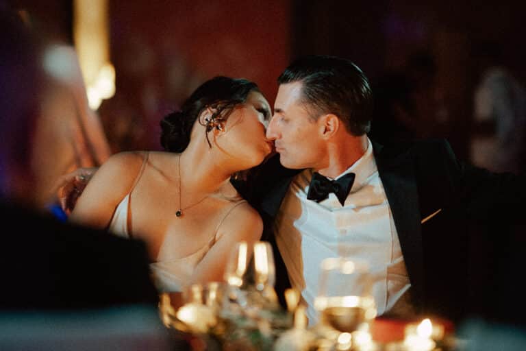 Suki and Brandon kiss at their candlelit wedding dinner in a villa near Marrakech.